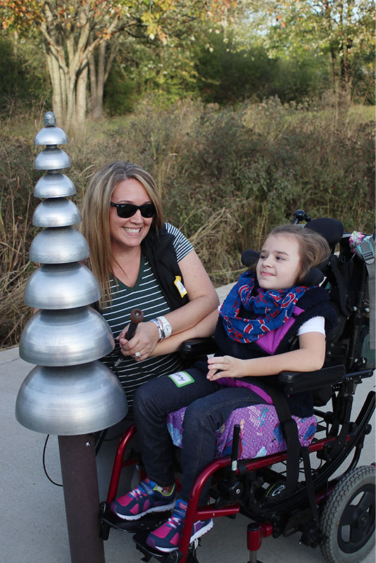little girl in a wheelchair with her mother playing in the sound garden