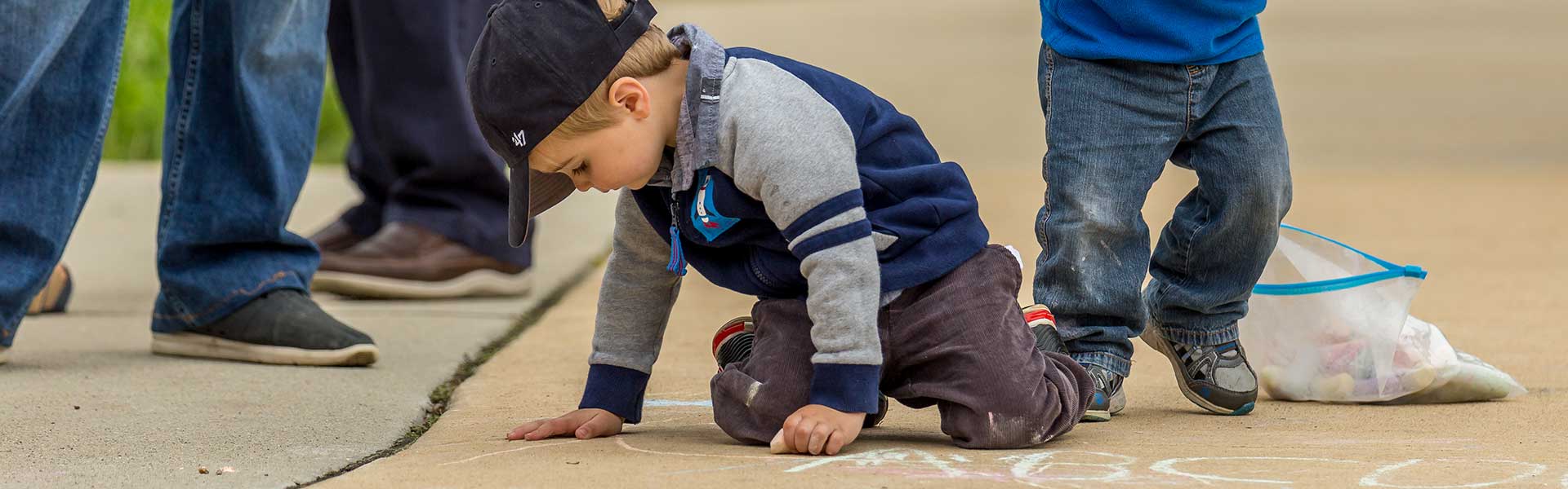 child drawing with chalk on the ground